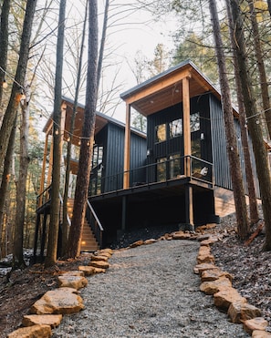 A cabin with a wooden deck and a staircase leading to a covered area.