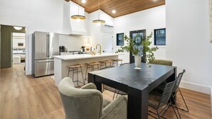 Una cocina moderna con una isla central, electrodomésticos de acero inoxidable y un comedor con mesa y sillas.