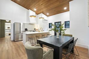 A modern kitchen with a central island, stainless steel appliances, and a dining area with bar stools.