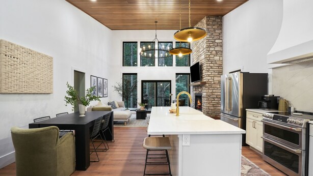 Una cocina moderna con una isla central, electrodomésticos integrados y una pared decorativa de piedra.