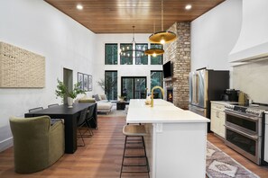 A modern kitchen with a central island, double ovens, and a stone wall.