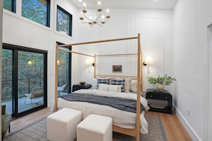 A modern bedroom with a four-poster bed, large windows, and a view of the outdoors.