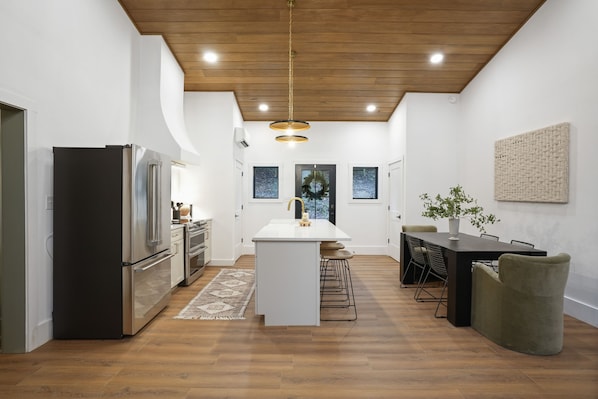 A modern kitchen with a central island, stainless steel appliances, and a dining area with a table and chairs.