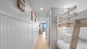 A narrow hallway with a bunk bed on the right, wooden slats, and a small table with chairs in the distance. - Sundestin 1008 (Destin)