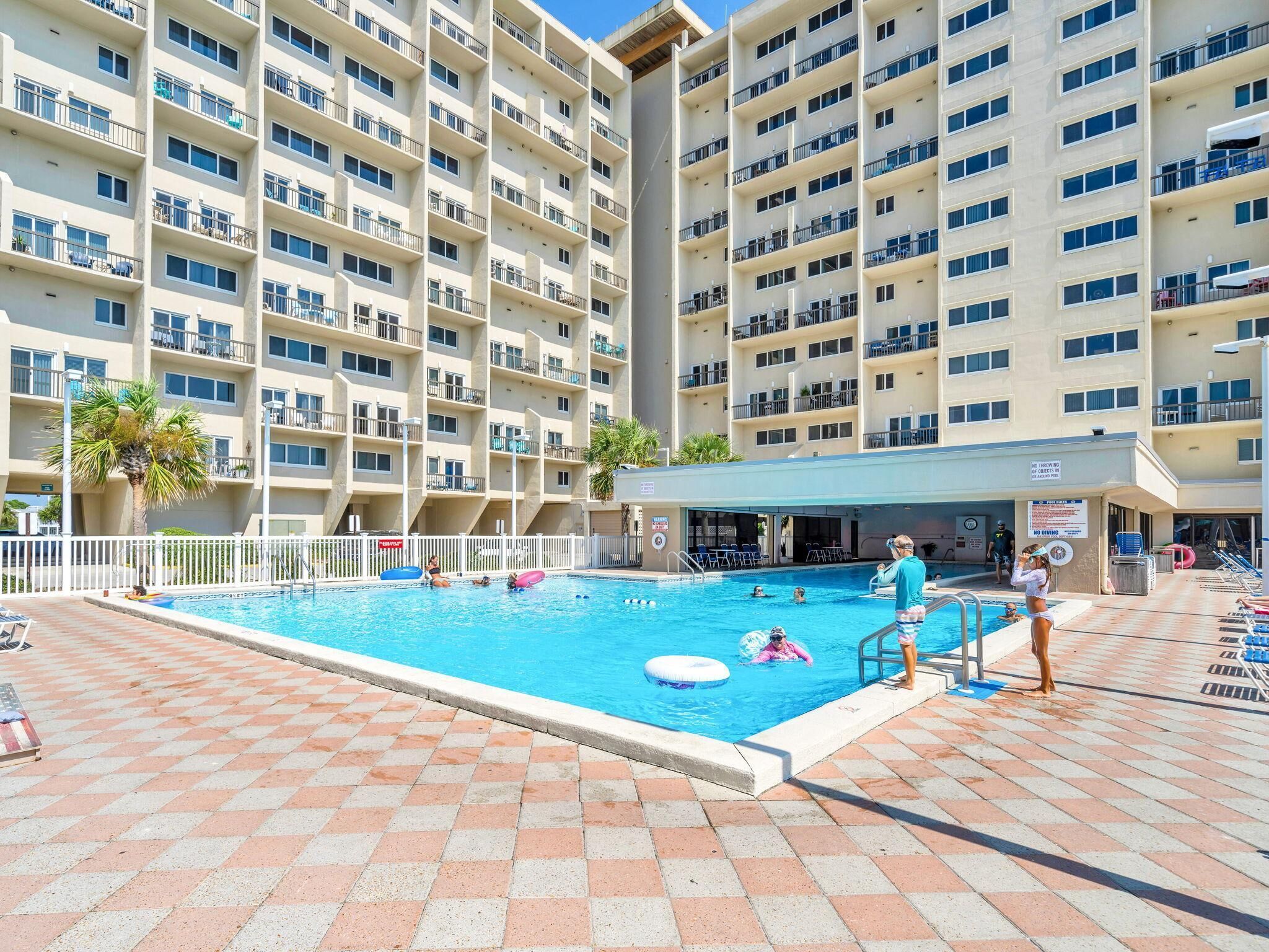Ein mehrstöckiges Hotel mit Schwimmbad, Außenbereich und überdachtem Bereich.