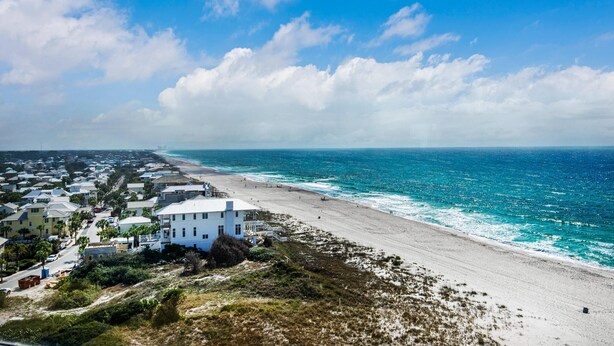 Eine Küstenstadt mit Strand, Häusern und blauem Himmel.