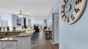 A spacious kitchen with granite countertops, a ceiling fan, and a large wooden clock on the wall. - Pelican Beach Terrace 807 (Destin)