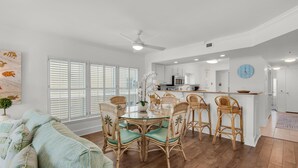 A spacious living room with a dining area, a kitchen, and a large window with blinds. - Sea Oats 601 (Fort Walton Beach)