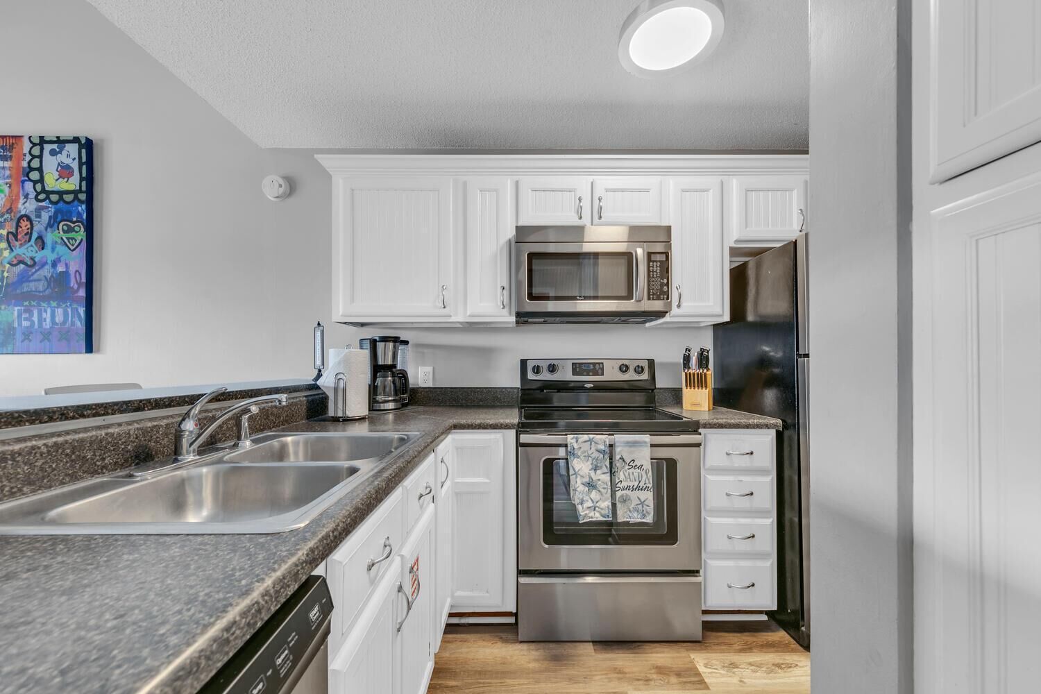 A modern kitchen with white cabinets, stainless steel appliances, and a granite countertop.