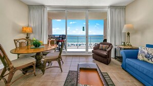 A hotel room with a balcony, a dining area, a sofa, and a TV. - Majestic Beach Towers 1-407 (Panama City Beach)