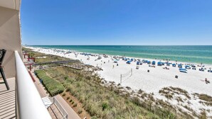 A beach with white sand, blue umbrellas, and a clear blue sky. - Majestic Beach Towers 1-407 (Panama City Beach)