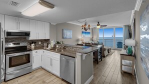A modern kitchen with white cabinets, stainless steel appliances, and a large island. - Majestic Beach Towers 1-1804 (Panama City Beach)