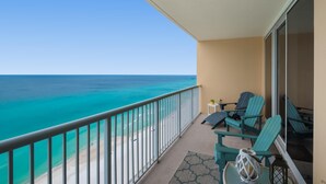 A balcony with a view of the ocean, two chairs, a small table, and a lantern. - Majestic Beach Towers 1-1804 (Panama City Beach)