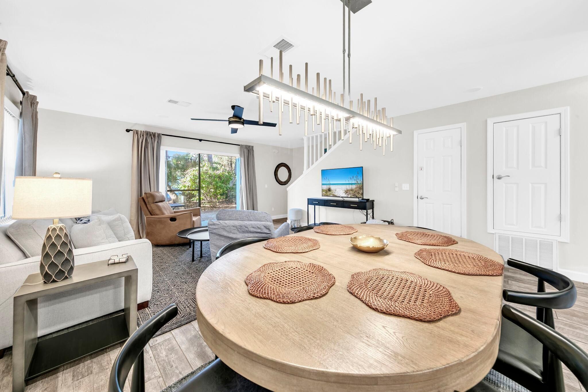 Una sala moderna con una mesa redonda de madera, un sofá y una zona de comedor con individuales tejidos.
