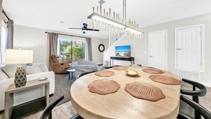 Un salon moderne avec une table ronde en bois, un canapé et un coin repas agrémenté de sets de table en fibres tressées.
