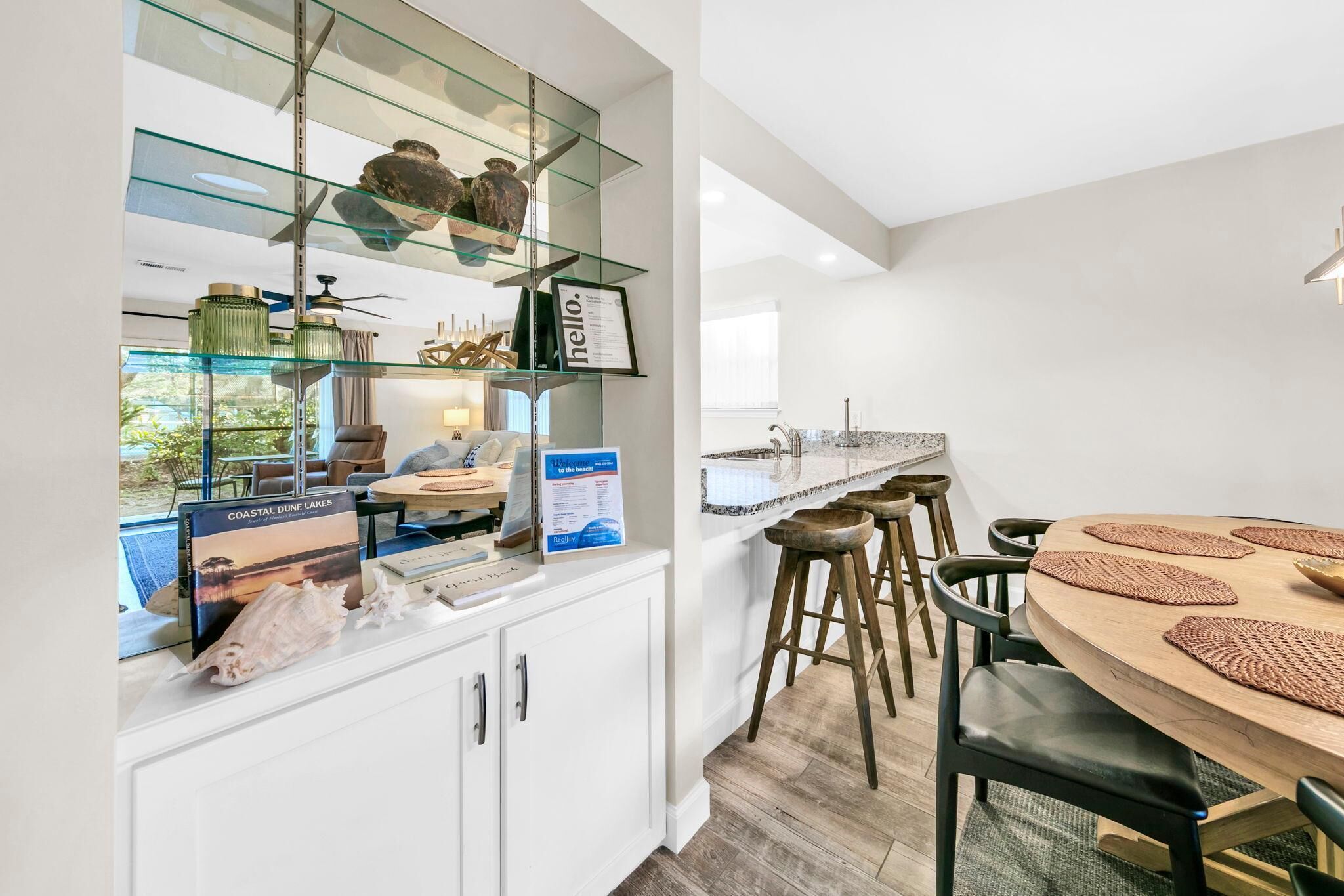 Une cuisine moderne dotée d’un meuble vitré, un coin repas avec une table ronde et un bar avec des tabourets.
