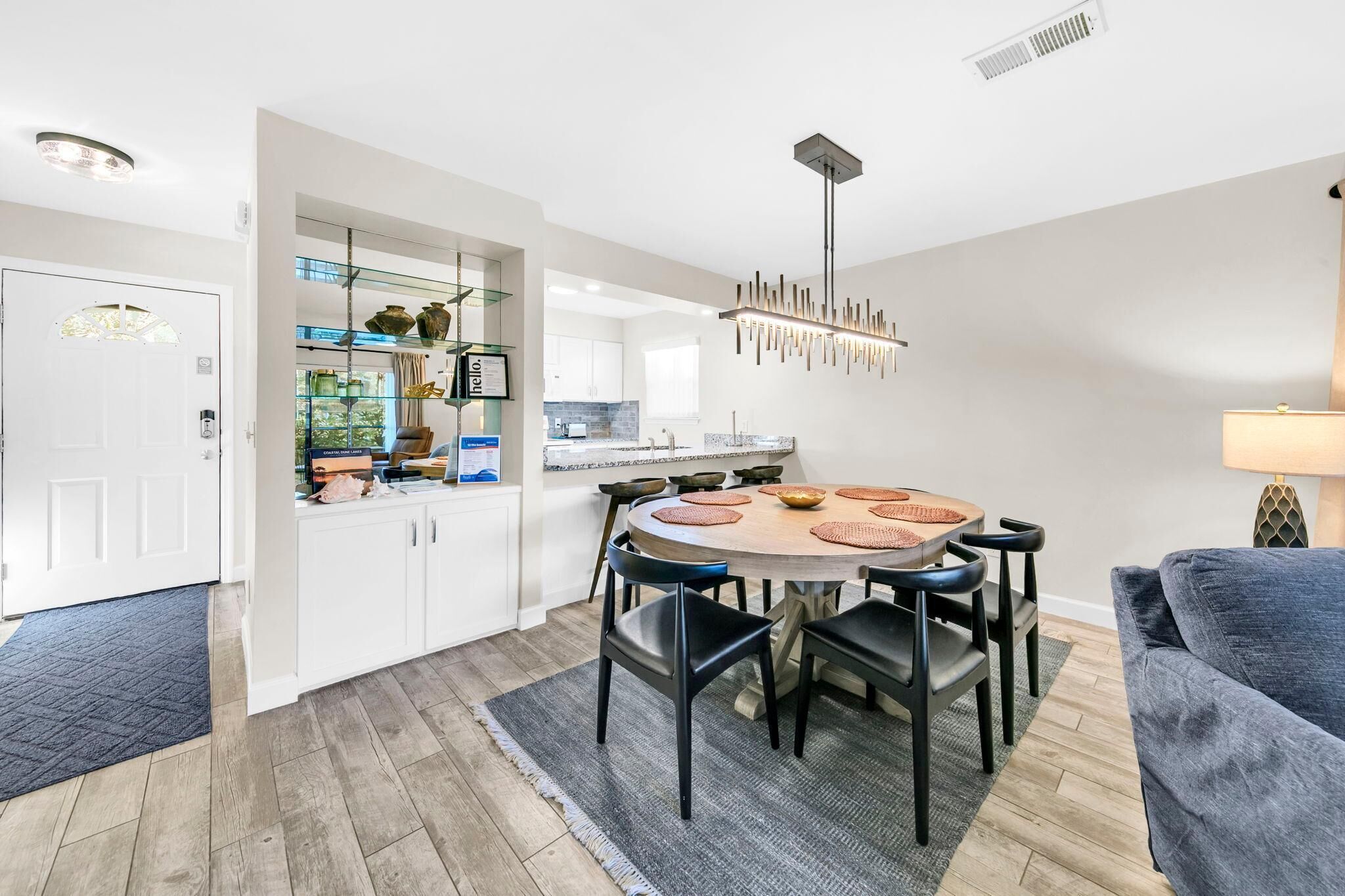 A modern kitchen with white cabinets, a round dining table with black chairs, and a pendant light.
