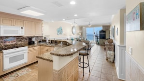 A spacious kitchen with granite countertops, a central island, and a view to the living area. - Boardwalk 508 (Panama City Beach)