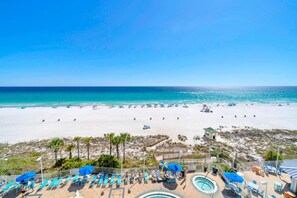 A beach resort with a pool area, sun loungers, and a view of the ocean. - Boardwalk 508 (Panama City Beach)