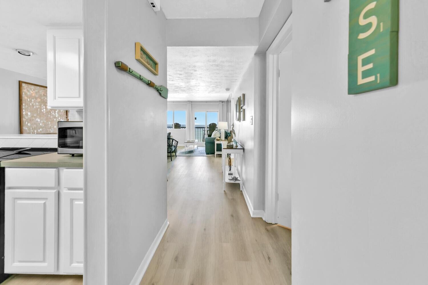 A modern kitchen with white cabinetry, a microwave, and a dining area with a table and chairs.