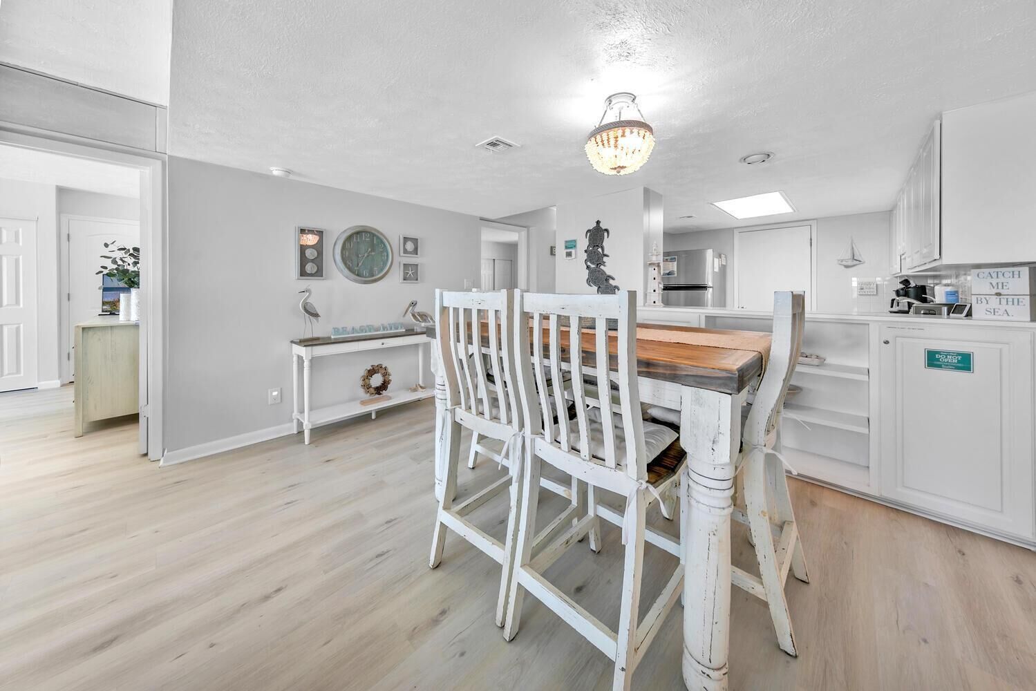 Een moderne keuken met witte kastjes, een houten eettafel en een kroonluchter.
