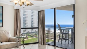 A spacious room with a large sliding glass door leading to a balcony with a view of the ocean and buildings. - Mainsail 234 (Miramar Beach)