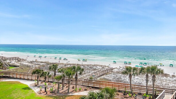 A beach view with a wooden boardwalk, palm trees, and beach umbrellas. - Mainsail 234 (Miramar Beach)