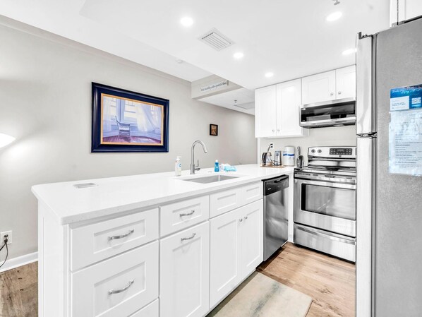 A modern kitchen with white cabinetry, stainless steel appliances, and a built-in dishwasher.