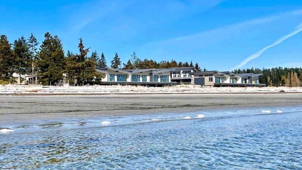 Une propriété située en bord de mer, avec une eau cristalline, une plage de sable et une rangée de maisons modernes.