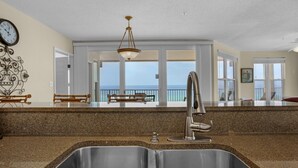A kitchen with a double sink, granite countertop, and a view of the balcony. - The Palms #601 (Fort Walton Beach)
