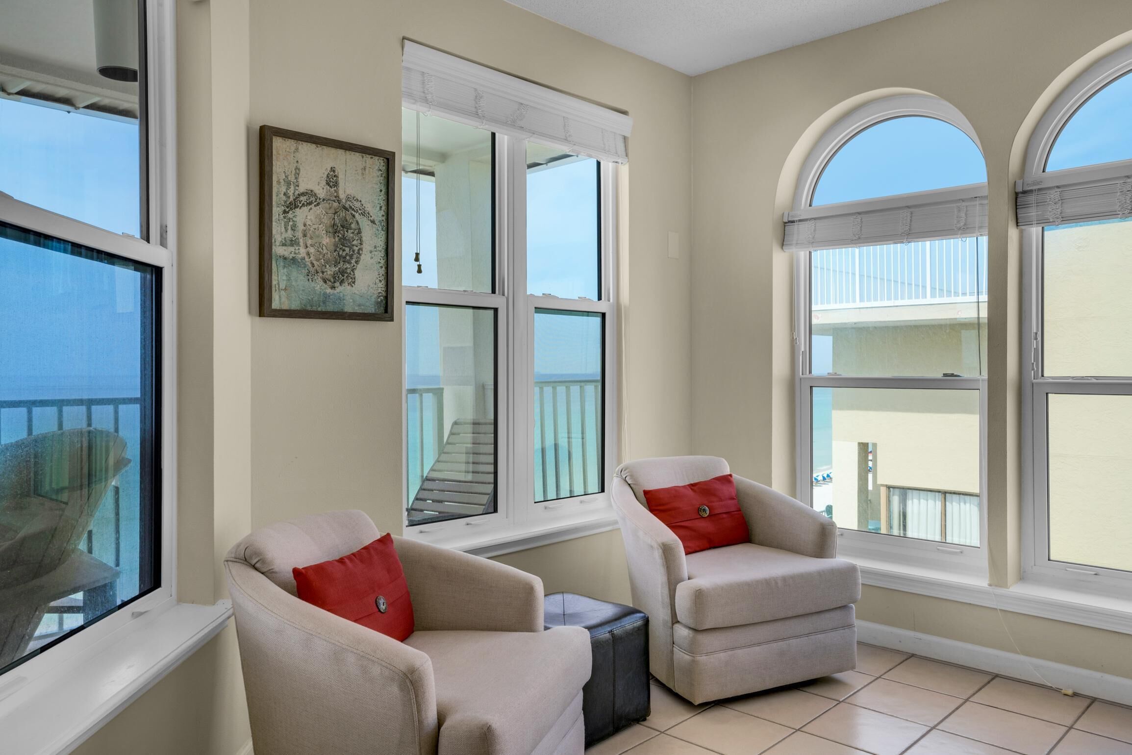 Une pièce avec deux fauteuils, une petite table et de grandes fenêtres donnant sur des balcons.