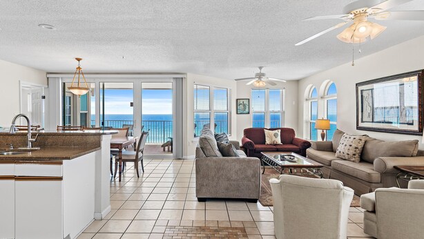 A spacious living area with a kitchen, dining area, and large windows offering a view of the ocean. - The Palms #601 (Fort Walton Beach)