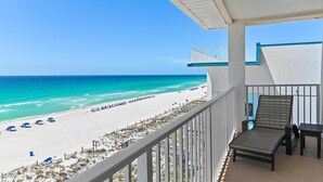 A balcony with a view of a beach, a chair, and a small table. - The Palms #601 (Fort Walton Beach)