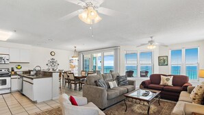 A spacious living area with a kitchen, dining area, and a large window providing a view. - The Palms #601 (Fort Walton Beach)