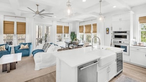 A modern kitchen with a central island, white cabinetry, and stainless steel appliances.