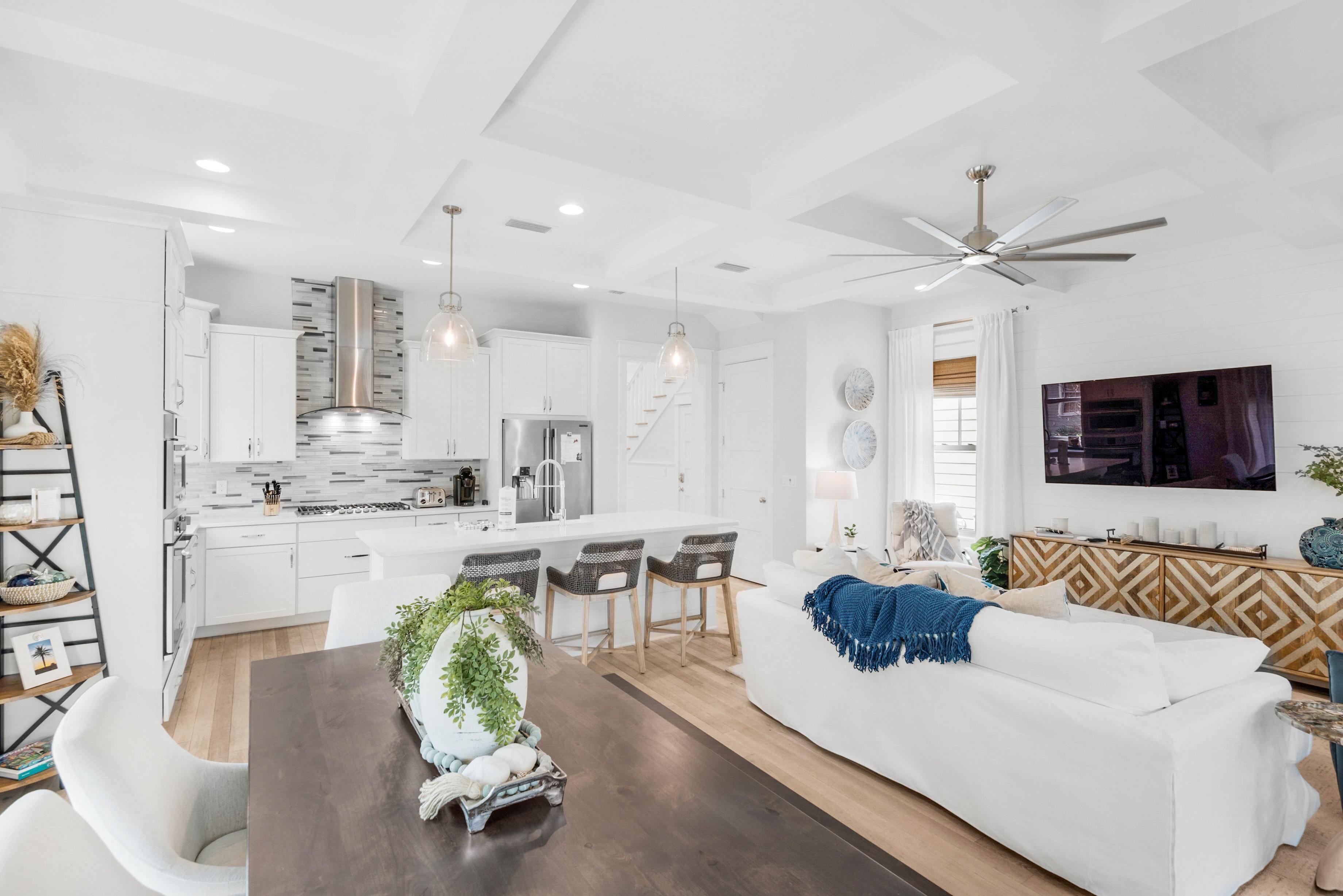 A modern kitchen with white cabinets, a stainless steel range hood, and pendant lighting.