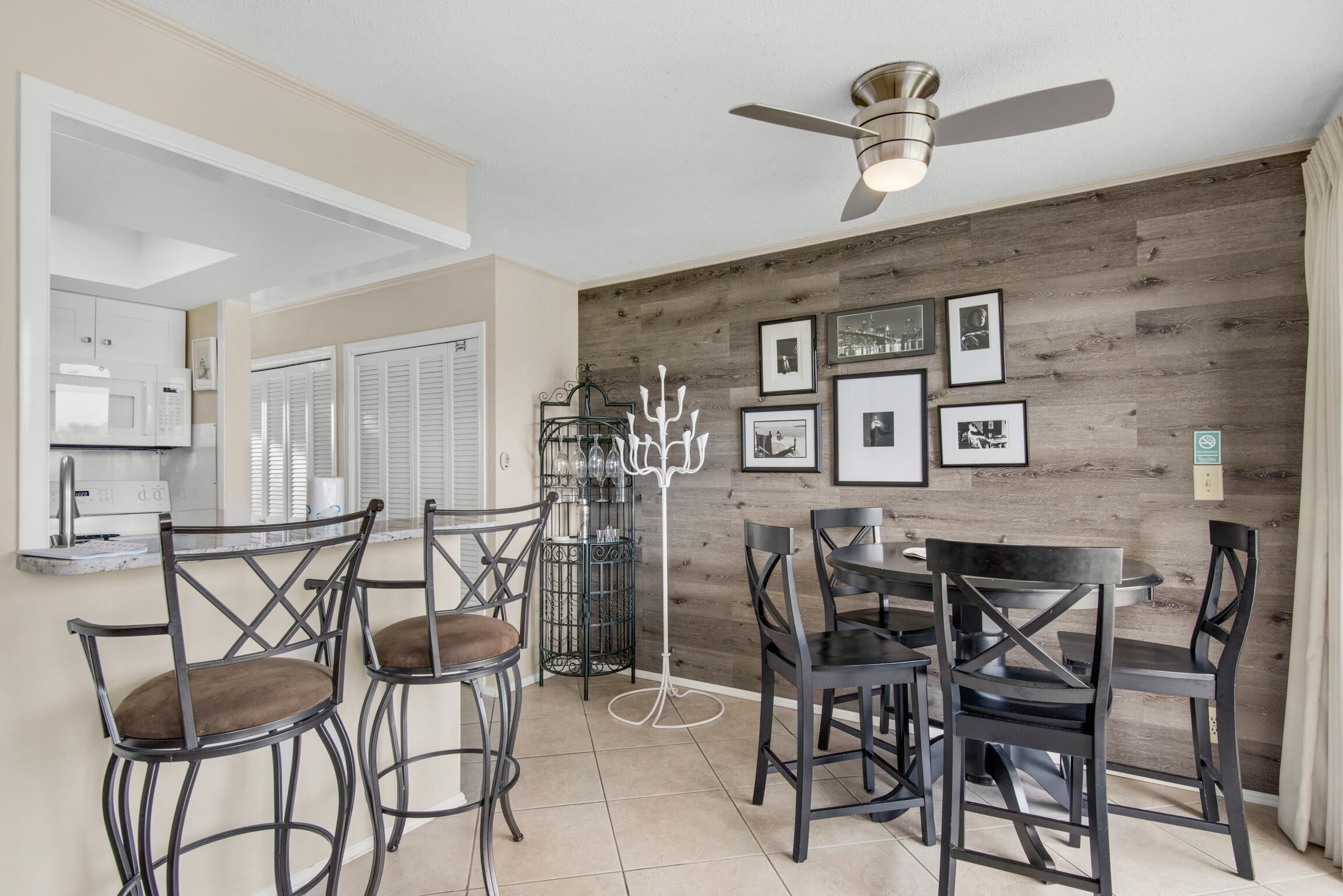 Un coin repas avec un mur en bois, des tableaux encadrés et un ventilateur de plafond.