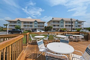 A deck with outdoor seating, a view of a multi-story building with balconies, and a clear sky. - St. Martin Beachwalk Villas 323 (Destin)
