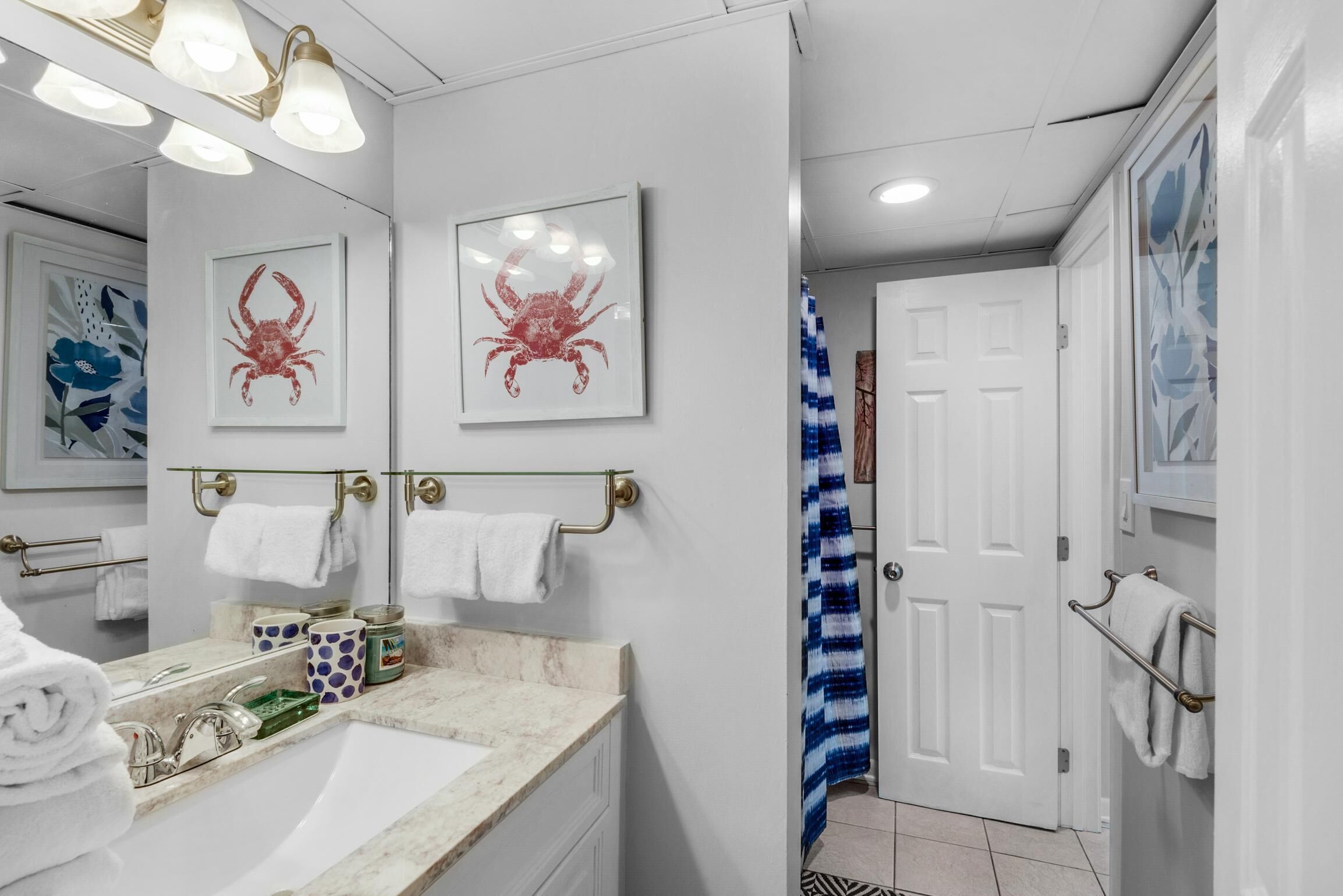 A bathroom with a sink, mirror, and two framed crab pictures on the wall.