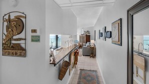 Een moderne keuken met een centraal eiland, een zithoek met een bank en een hal met decoratieve wandkunst.