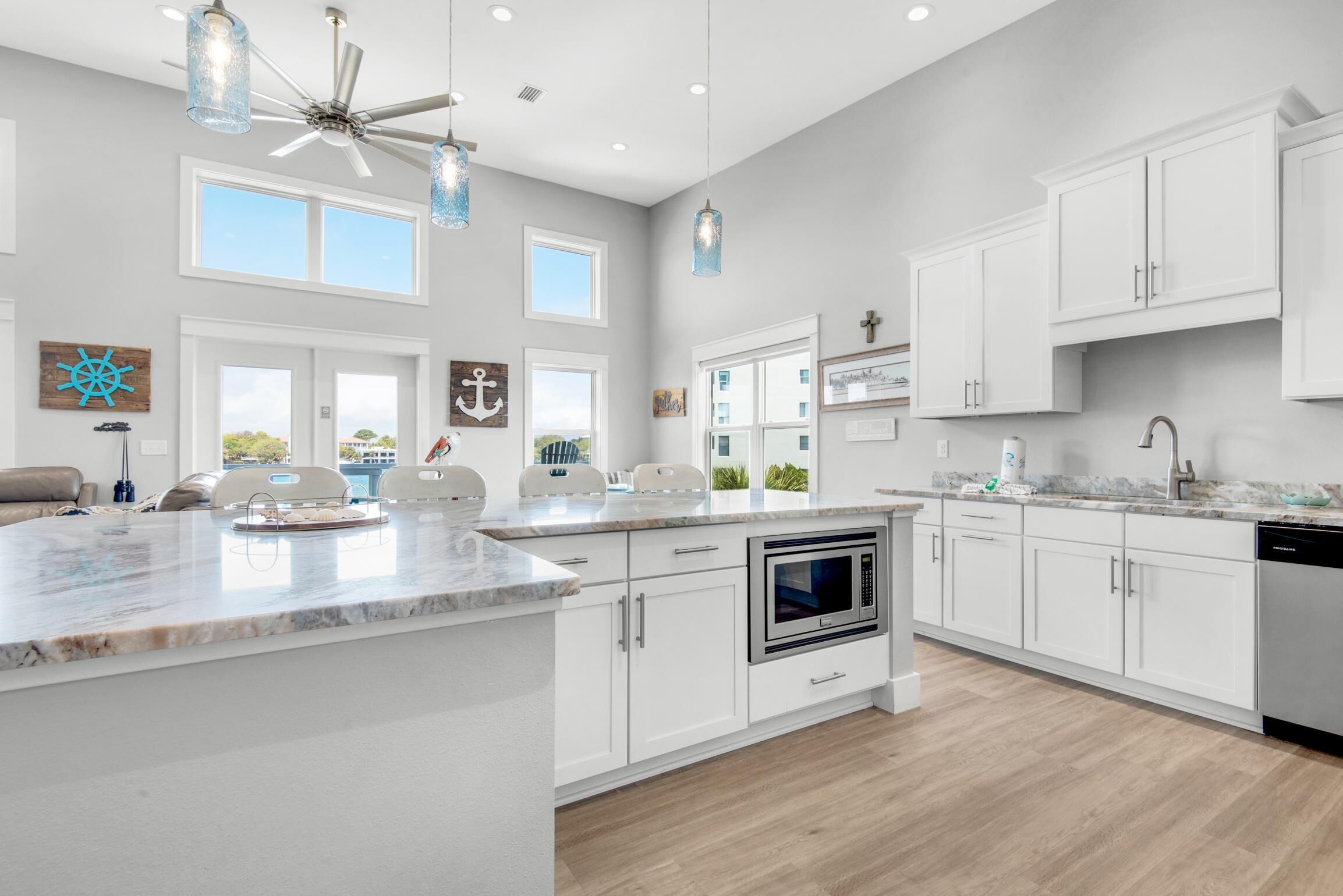Une cuisine moderne avec des meubles blancs, un grand îlot central et des luminaires suspendus.