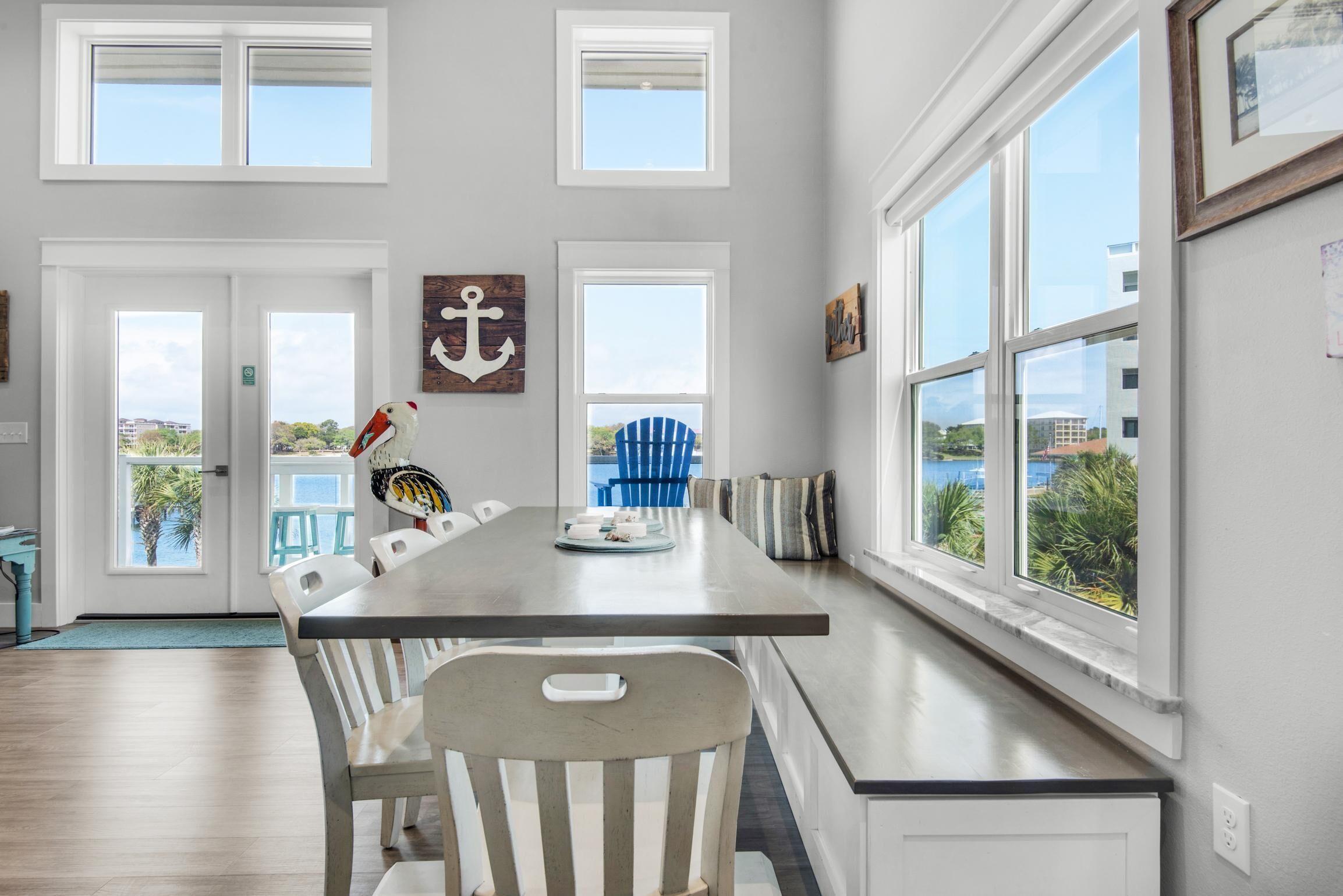A dining area with a long table, white chairs, and a view of the outdoors.