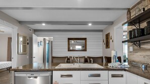 A modern kitchen with a double sink, white cabinets, and a built-in dishwasher. - Emerald Isle 302 (Fort Walton Beach)
