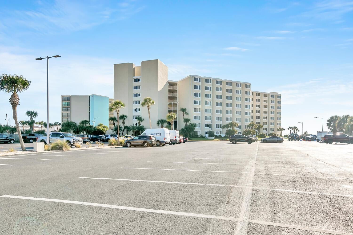 Un parking avec un grand bâtiment en arrière-plan.