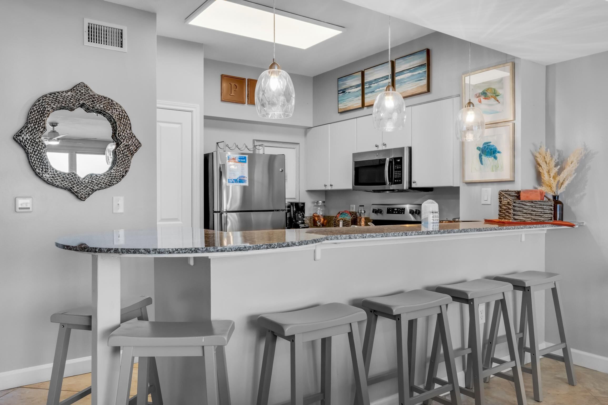 A modern kitchen with a central island, bar stools, stainless steel appliances, and decorative wall art.