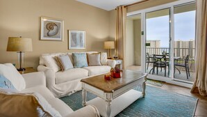 A spacious living room with a white sofa, a coffee table, and a balcony with outdoor furniture. - Ariel Dunes II 904 (Miramar Beach)