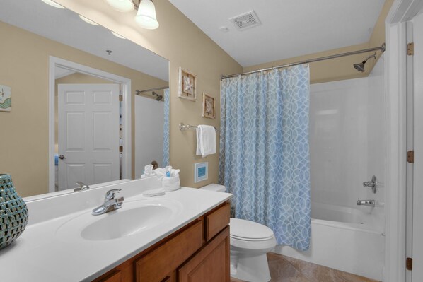 A bathroom with a white sink, vanity, and toilet. There is a shower curtain and a bathtub. - Ariel Dunes II 904 (Miramar Beach)