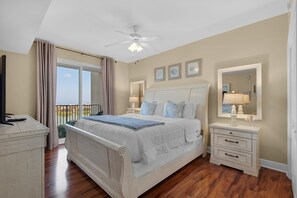 A bedroom with a large bed, a ceiling fan, a nightstand with a lamp, and a view of the outdoors. - Ariel Dunes II 904 (Miramar Beach)