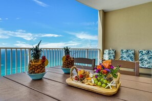 Ein Balkon mit Tisch, gedeckt mit tropischen Früchten, einer Obstplatte und einer Blumenkomposition.