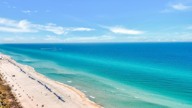 Ein Strand mit klarem türkisblauem Wasser und einem Sandufer.